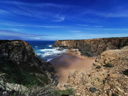 Extensive coastal view with dramatic cliffs and deep blue ocean under a clear sky, hiking on the