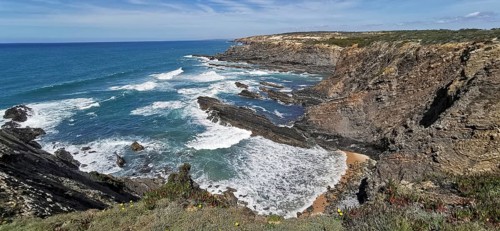 Dramatic coastline with rugged cliffs and rushing waves under a clear sky, hiking the Fisherman's