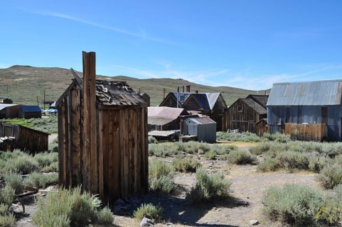 An abandoned village with several wooden houses, toilet, outhouse in the foreground, in a natural,