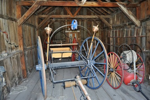 Antique tools and wagons in an old, abandoned wooden barn, fire engines, Bodie Ghost Town,