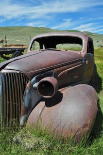 Front view of abandoned rusty car wreck, Chevrolet Coupé, under blue sky, Bodie Ghost Town,