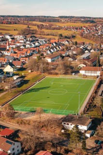 Green sports ground in a village surrounded by houses and hills seen from the air, Wimberg, Calw,