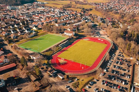 Stadium with soccer field and red track adjacent to a residential area, Wimberg, Calw, Germany