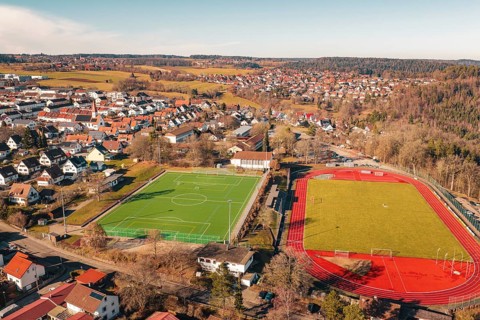 Aerial view of two neighboring sports fields in a village with soccer field and running track,