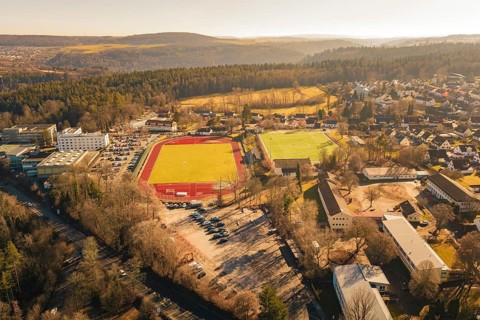 Comprehensive view of the city and surrounding area with sports fields and forest from the air,
