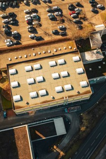 Aerial view of a parking lot and roof of a sports hall in sunshine in a winter environment,