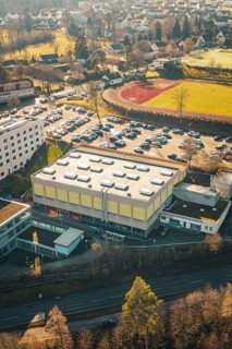 School complex with sports field and large parking lot, surrounded by winter countryside, Wimberg,