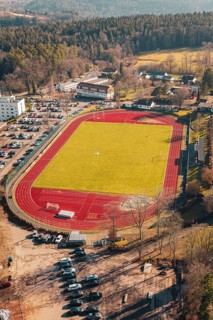 Red track with green grass and surrounding forest in a village, seen from the air, Wimberg, Calw,