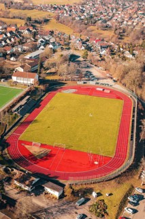 Sports field with red track and green field in a rural village seen from the air, Wimberg, Calw,