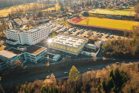 Picture of a school complex with a sports hall, parking lot and a sports field in a wintry