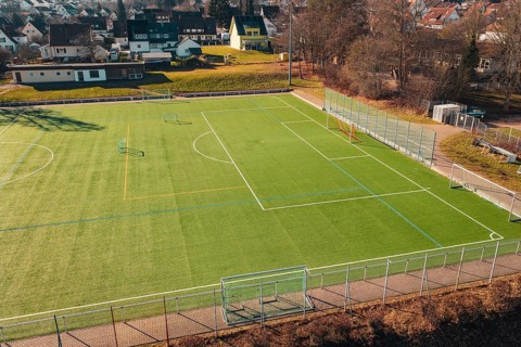 Sports field with soccer field and fences, surrounded by trees and villages, Wimberg, Calw, Germany