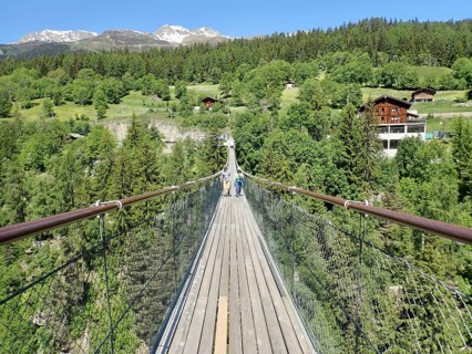 Extensive suspension bridge in idyllic mountain and forest areas in sunny weather, Goms Bridge,