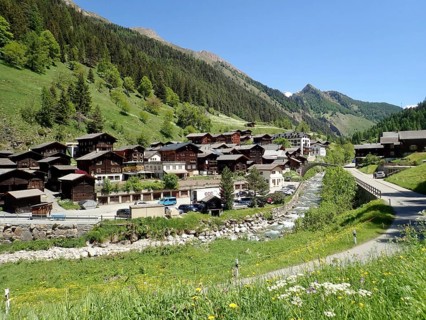 Alpine village with traditional architecture, nestled in green mountains and dense forest, Binn,