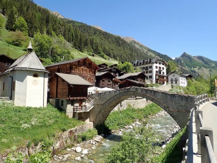 Mountain village with picturesque stone bridge and river in alpine landscape with clear sky, Binn,