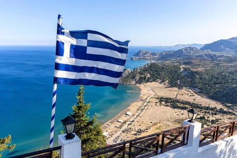 View of Tsambika beach from above with Greek flag Mediterranean seaside island of Rhodes, Greece