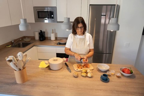 Woman preparing fresh vegetables on kitchen counter, chopping carrots and potatoes for homemade