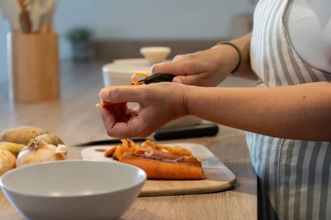 Hands peeling carrots for homemade meal. Clean eating, simple ingredients and healthy lifestyle
