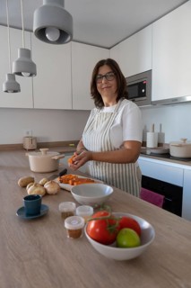 Vertical portrait of woman peeling carrot on kitchen counter. Cozy home cooking scene, healthy