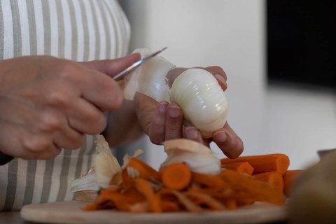 Close up of hands peeling onion for homemade meal. Simple ingredients, food preparation and
