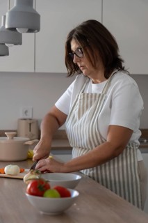 Woman chopping onion on kitchen counter with selective focus on woman. Food preparation and