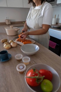 Vertical close up of hands peeling fresh carrot on cutting board in modern kitchen. Healthy