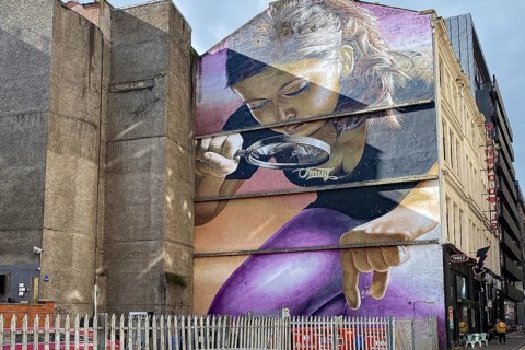 Large wall painting of a woman with magnifying glass in an urban setting, mural, street art,