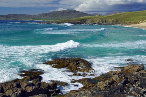 Dramatic coastal scene with breaking waves over rocky shore under cloudy sky, Isle of Harris, Outer