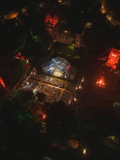Aerial view of an open-air concert at night with illuminated spectators