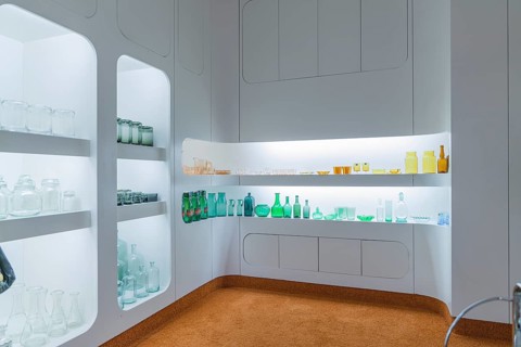 Interior with illuminated shelves full of glass bottles, modern white design