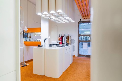 Modern kitchen with orange carpet and unusual lighting, visible behind doors
