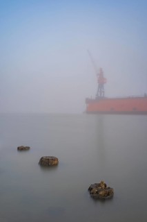 View of old weathered wooden pegs on a dry dock at the port of America on which a crane stands in