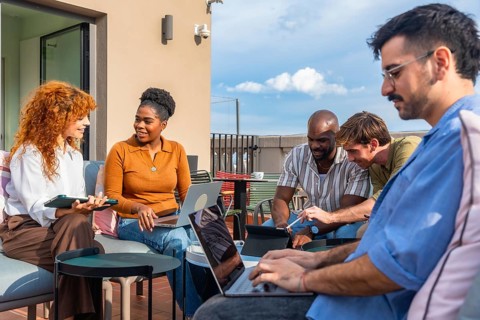 Group of diverse business people using laptops and tablets while working together on a