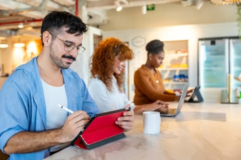 Diverse colleagues working on personal devices in a modern office, focusing on tasks and