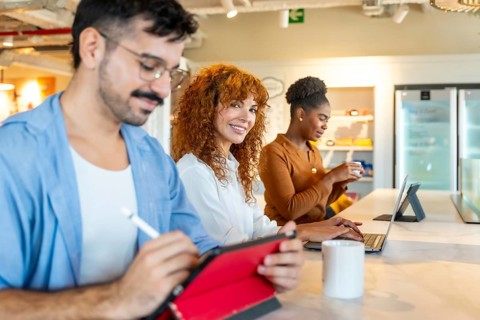 Group of diverse business professionals using digital devices and interacting during a break in a
