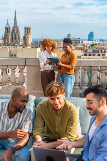 Diverse colleagues are brainstorming and working together with a laptop and tablet on a rooftop,