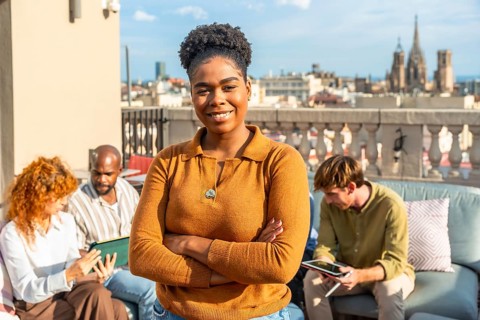 Confident black woman leader standing with arms crossed, smiling at the camera while her diverse
