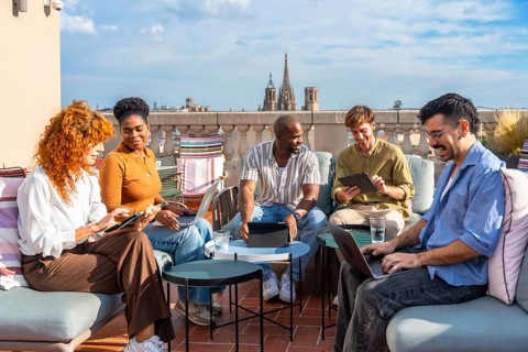Diverse business colleagues working remotely from an outdoor rooftop office during a break,