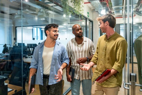 Diverse group of male colleagues engaging in a friendly discussion while walking through a modern