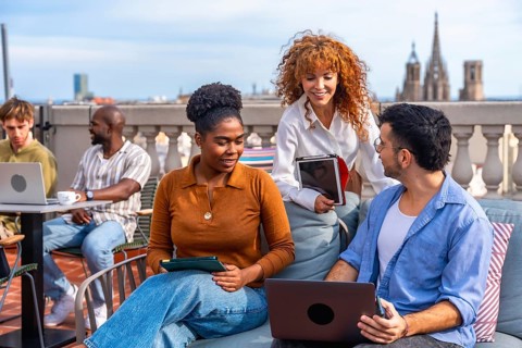 Diverse business professionals collaborating and networking on a barcelona rooftop terrace, using