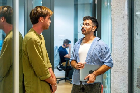 Two male colleagues engaging in an informal discussion during a break in a modern coworking space,