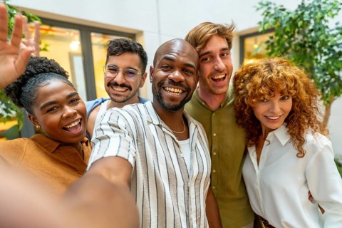 Group of happy diverse business colleagues smiling and looking at camera while taking a selfie