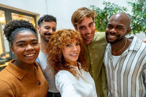 Diverse group of smiling business people looking at camera, capturing a self portrait together