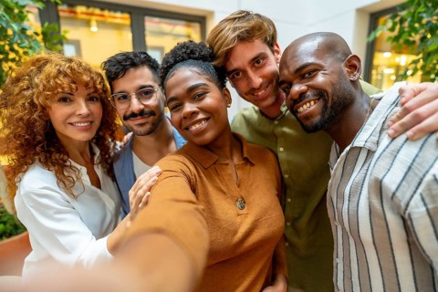 Diverse colleagues enjoying a moment together, smiling and embracing while posing for a self