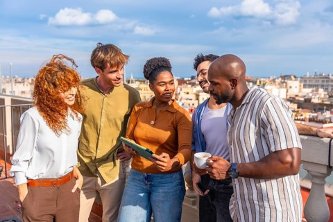 Diverse business people standing on a sunny urban rooftop, networking and collaborating while
