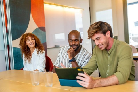 Diverse business people engaging in a constructive indoor meeting, looking at a digital tablet and