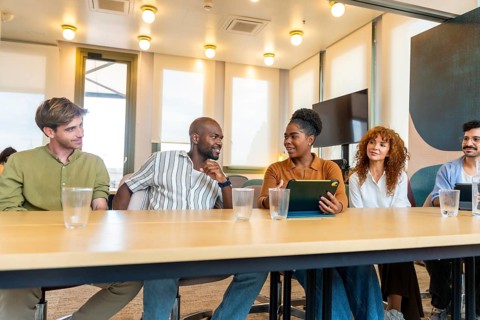 Diverse group of business colleagues sitting at a table during a break or meeting, discussing work