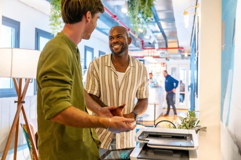 Two diverse male colleagues having a friendly discussion and smiling during a relaxed break in a