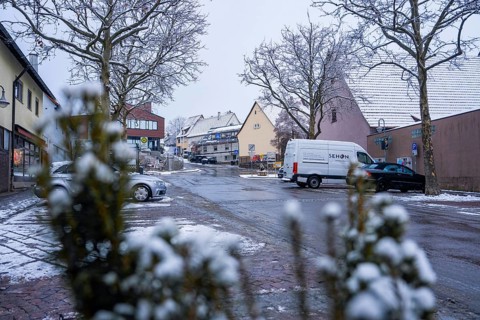Snowy village road with parked cars and traditional ensemble of houses, Gechingen, Calw district,