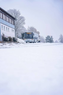Snowy road with a bus and buildings in the background, cloudy, Gechingen, Calw district, Germany