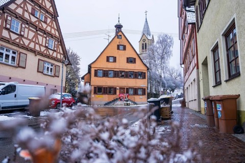 Snowy village road with traditional architecture and church in the background, Gechingen, Calw